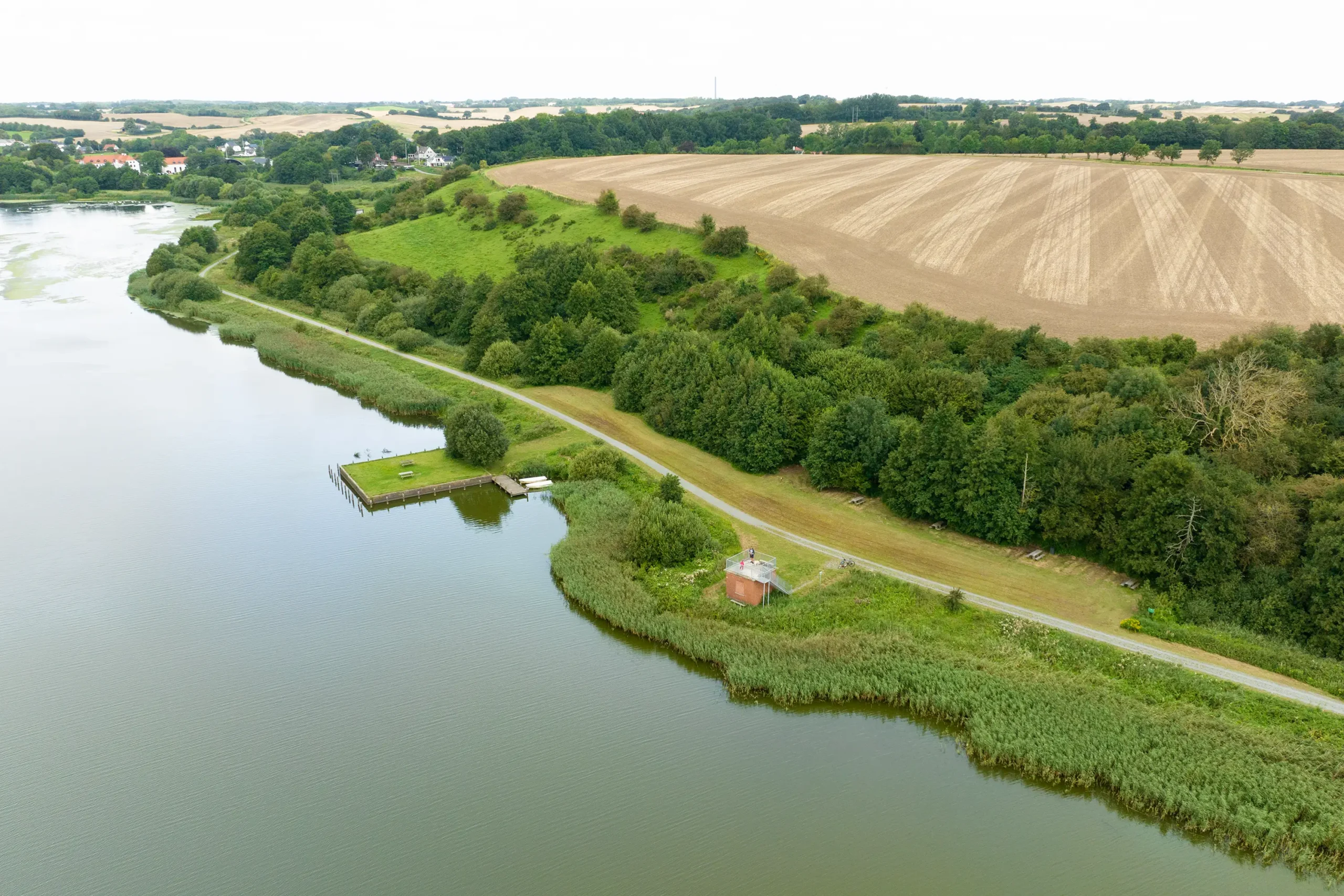 Dronevideo og dronefotos taget af landbrug og en sø i Jylland. Flot landskabsbillede.